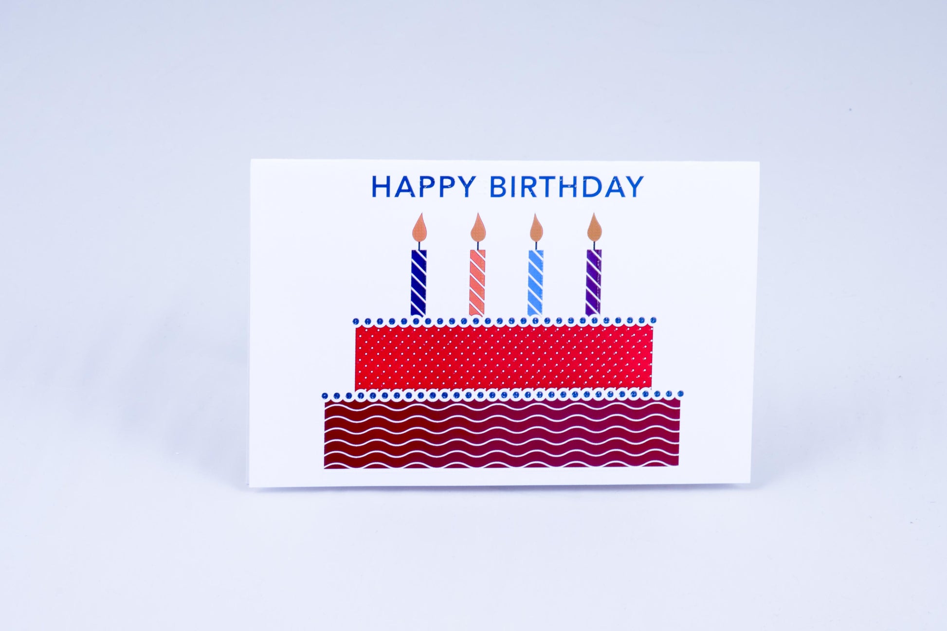 A birthday cake with 4 lit candles & greeting on top