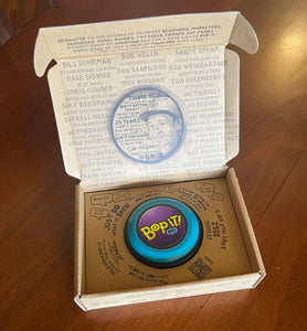 Bop It Button in classic '90s colors (teal, purple, and black) in its box